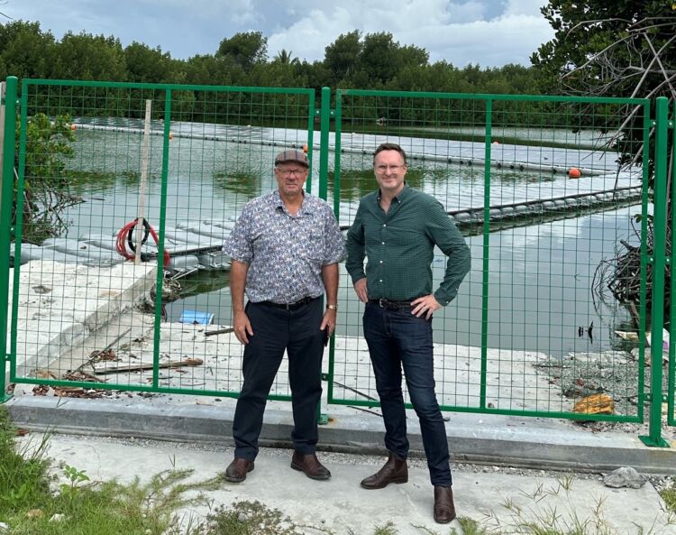 David Irvine & Shawn Thompson stand in front of a floating solar panel array